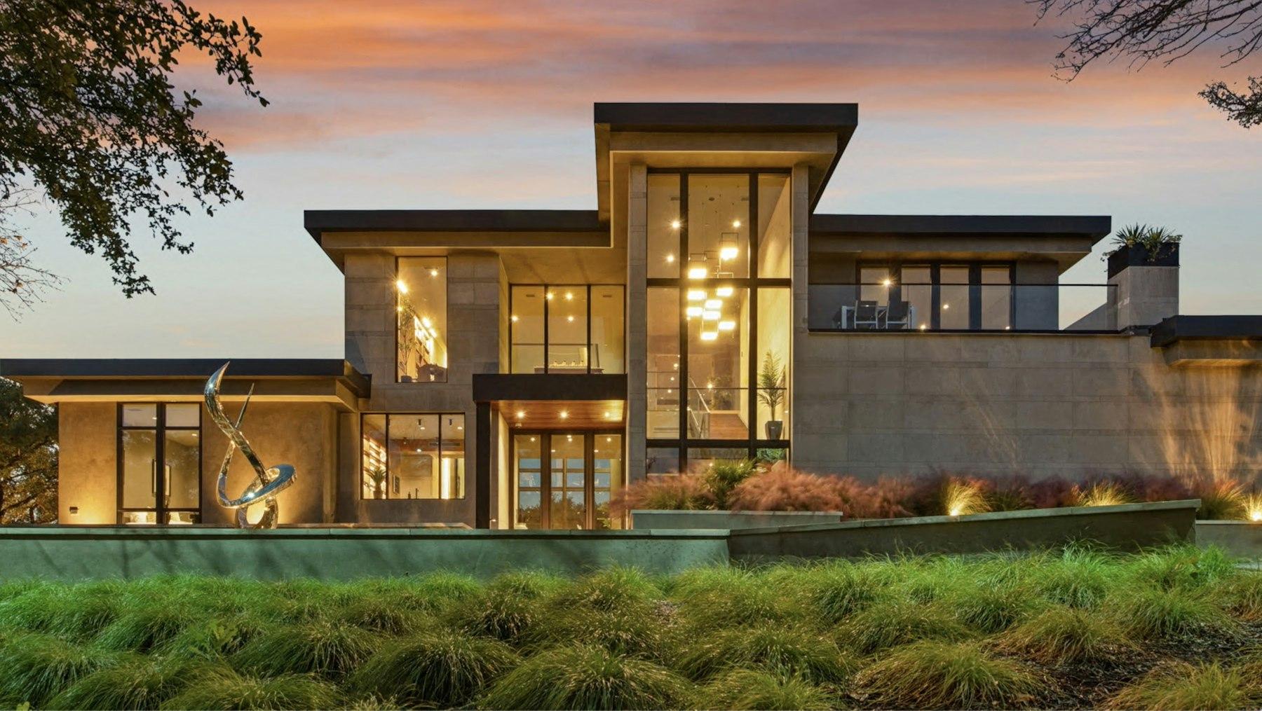 Modern residence at dusk, floor-to-ceiling glass and warm architectural lighting